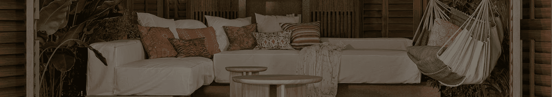 Exterior view of a modern house at dusk, featuring a paver driveway, artificial grass, stone veneer pillars, and windows reflecting the sunset.