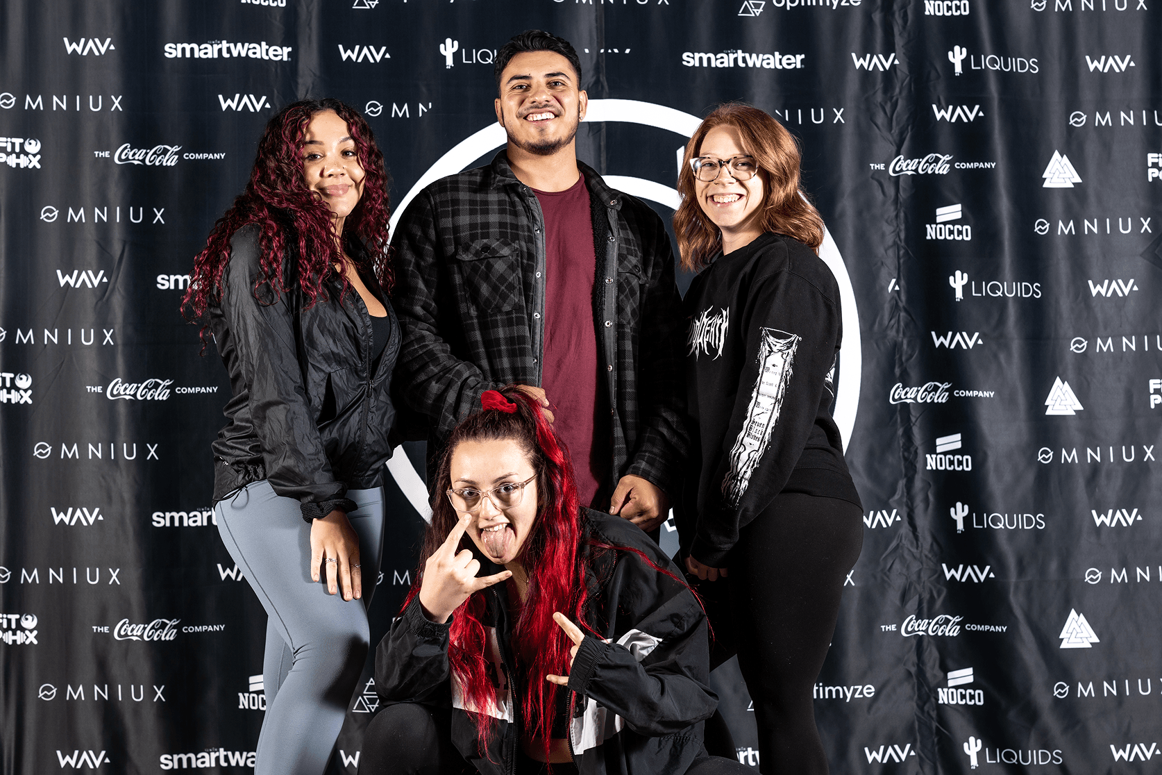 A group of 4 people standing in front of a Step and Repeat banner